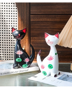 Detail of hand-painted wooden cat figurines with pink lotus and green leaf patterns
