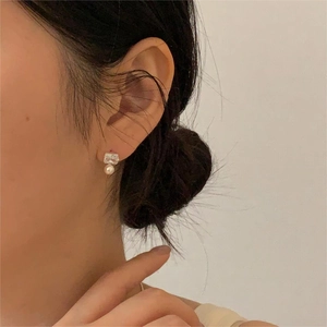 Close-up of elegant square crystal and white pearl drop earrings on a model ear