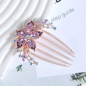 Rose gold five-tooth hair comb with purple floral rhinestones on a minimalist white tray
