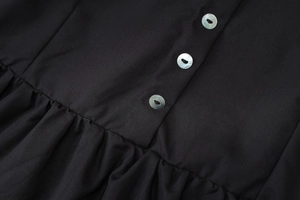 Detailed macro view of black fabric texture with pearlescent buttons and pleated design