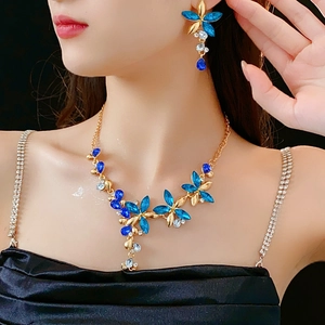 Close-up of model wearing vintage gold jewelry set with blue floral crystals and earrings