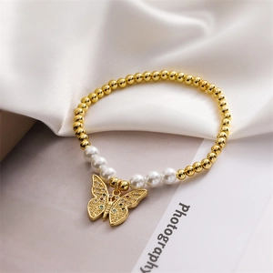 Close-up of a pearl and gold bead bracelet featuring a minimalist butterfly charm