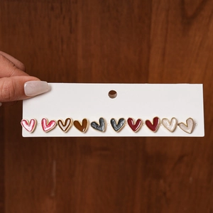 Close-up of ten-piece heart-shaped enamel stud earrings set in assorted warm colors