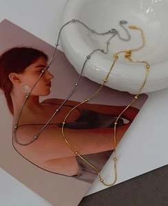 Detail of gold and silver snake bone necklaces with metal beads on a white ceramic plate