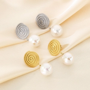 Macro shot of gold and silver spiral textured metal earrings with large white pearls