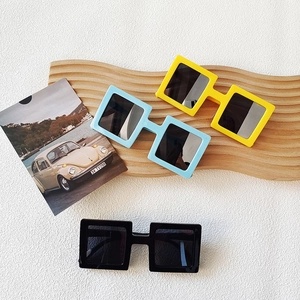 Fashionable square frame sunglasses in yellow, blue and black on a wooden display stand