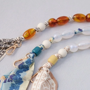 Detail of silk scarf beaded bag strap with metallic spring buckle and acrylic charms