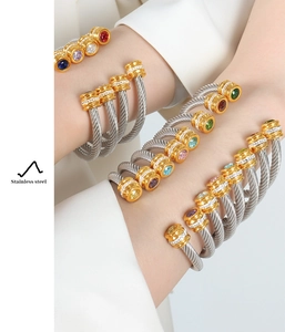 Close-up of dual-tone stainless steel cable bracelets with multicolored stone settings