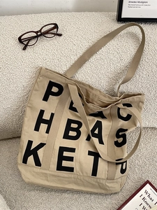 Khaki canvas tote bag with black letter print on white fleece background