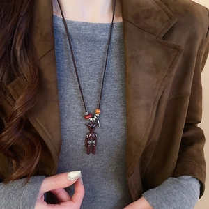 Detail of cute brown bear pendant necklace on model with beaded sweater chain accents