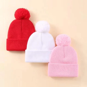 Tre berretti in maglia per bambini con pompon in rosso, bianco e rosa per l'autunno