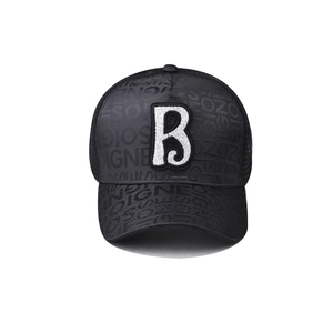 Detail of black baseball cap featuring sequined letter B patch and embossed fabric texture