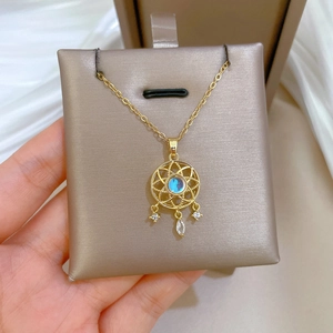 Close-up of golden dreamcatcher necklace with iridescent gem on champagne satin pad