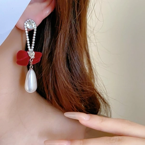 Detail of elegant bow earrings with pearls and rhinestones on model's ear