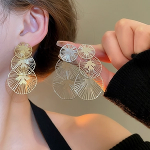 Vue détaillée des boucles d'oreilles dorées à triple couche avec texture de métal brossé