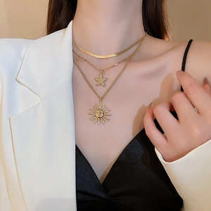 Detailed view of layered gold necklace with starfish and sun relief pendants for women