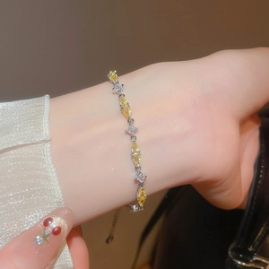 Detailed close-up of sparkling pear-cut yellow and white zircon bracelet on a wrist