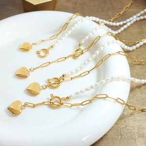Minimalist 18k gold plated titanium heart pearl necklace set on a ceramic tray