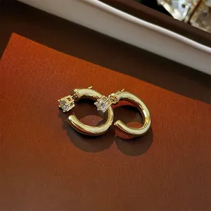 Macro shot of 18K gold C-shaped earrings featuring round-cut sparkling cubic zirconia