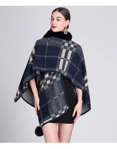 Detail of faux rabbit fur collar and pom-pom trim on navy blue plaid knit poncho