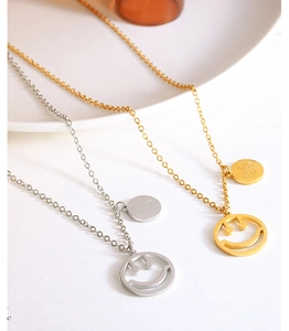 Primer plano de collares de cara sonriente oro y plata con colgantes Good Luck grabados