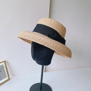 Elegant natural raffia sun hat with wide brim and black ribbon bow on display