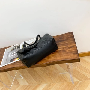 Elegant black leather tote bag with V-shaped ripple stitching on a designer bench