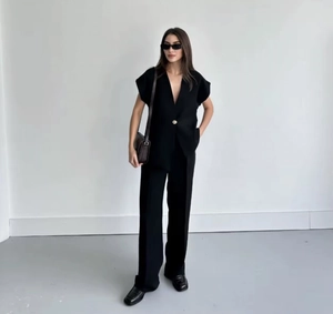 Detail of a chic black two-piece set featuring a single-button vest and wide-leg trousers