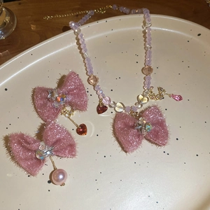 Detail of pink and purple fabric bow jewelry set with pearls and crystals in a beige dish