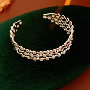 Dettaglio del bracciale aperto argento a tre strati di perline su scatola di velluto