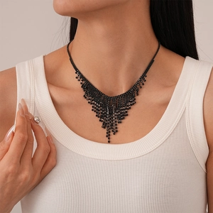 Detailed close-up of a black rhinestone tassel necklace with elegant V-shaped drape on a model
