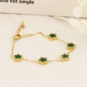 Detail of gold bracelet with green star pendants and cubic zirconia on white background