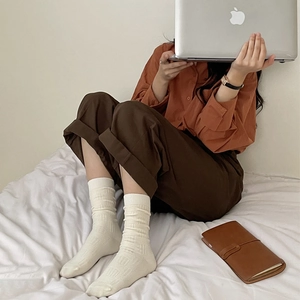 Cozy cream-colored mid-calf knit socks with square texture on white bedding