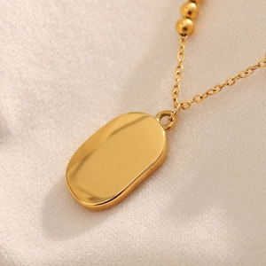 18K gold plated stainless steel sun pendant necklace with small gold beads on beige fabric