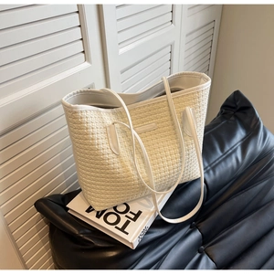 Close-up of white woven tote bag texture with slim double handles on a black leather seat