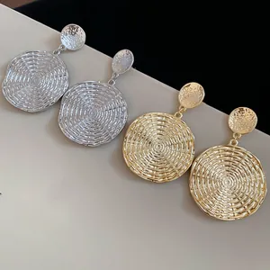 Detailed view of gold and silver round earrings with radiating spiral textured patterns