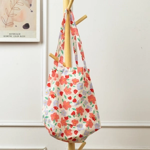 Detail of floral canvas tote bag hanging on a wooden hanger in a cozy home setting