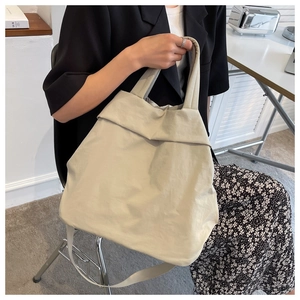 Detailed shot of beige nylon tote bag on shoulder showing large capacity and texture
