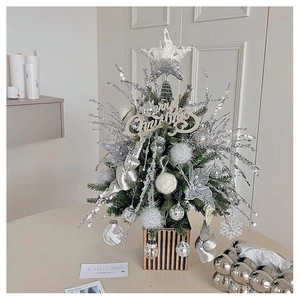 Detail of a silver mini Christmas tree with sequins and Merry Christmas sign in a pot