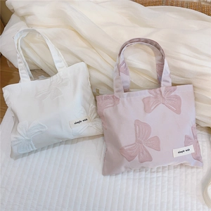 Detailed close-up of bow knot embroidery and brand label on satin mini tote bags