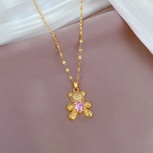 Macro detail of gold bear pendant with pink heart gemstone and sparkling stone accents