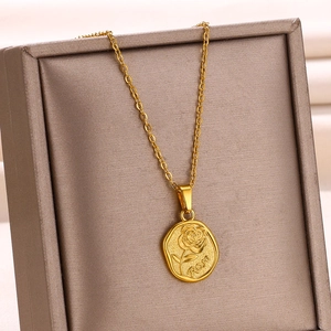 Vue macro du pendentif ovale en or avec rose en relief en acier inoxydable et sa chaîne