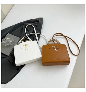 Détail du relief croco sur des sacs blanc et marron avec pendentifs de cerf dorés