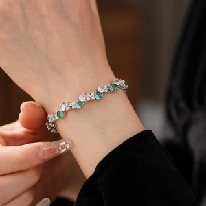 Macro shot of a twisted zircon tennis bracelet with green and white gems on a female wrist