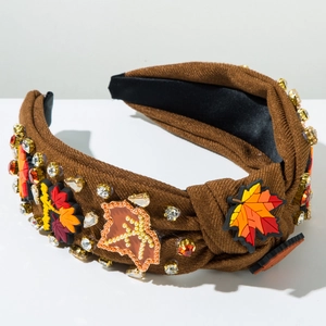 Détail d'un serre-tête noué marron avec feuilles d'érable, strass et perles d'automne