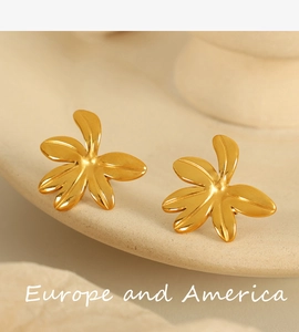 Detail of 18K gold plated vintage leaf stud earrings on a textured ceramic pedestal