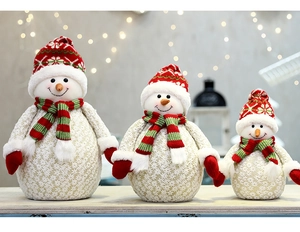 Tre pupazzi di neve in peluche con motivi in pizzo, cappelli rossi e sciarpe a righe