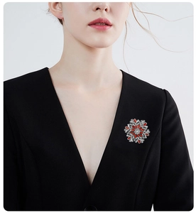 Detailed view of a red and white snowflake brooch pinned on a black suit lapel
