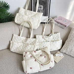 Detailed view of cream quilted cotton tote bags with floral and heart embroidery details