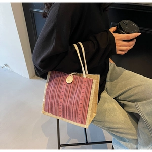 Close-up of linen tote bag with ethnic pink stripes and a wooden button closure